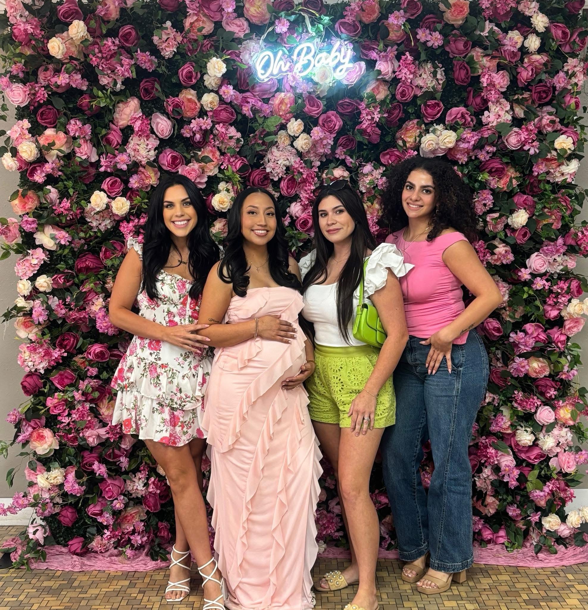 Baby shower with lush pink floral wall and neon Oh Baby sign